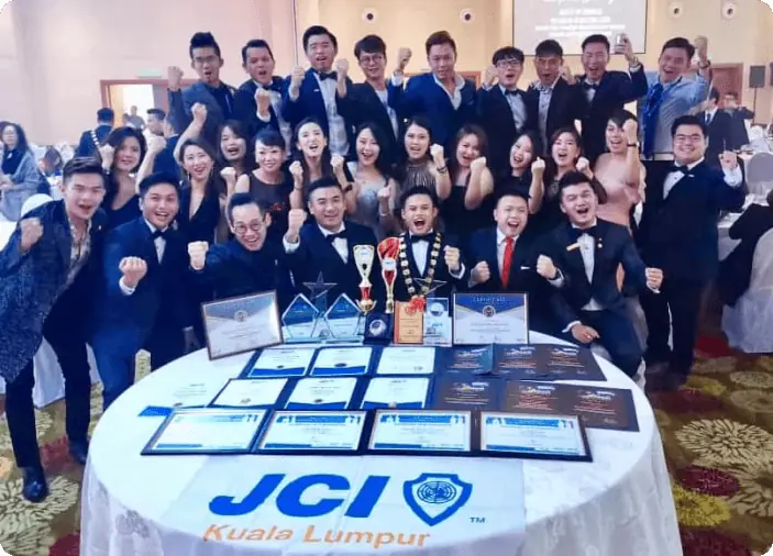 JCI Kuala Lumpur members in formal dress celebrating with trophies